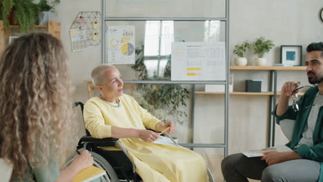 positive businesswoman in wheelchair talking with colleagues