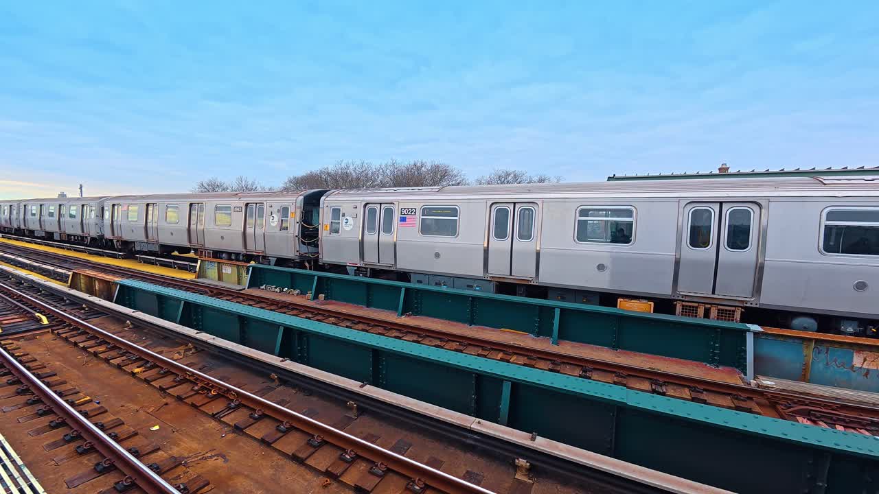 Vista laterale di vagoni della metropolitana argentati su binari sopraelevati. Moderni vagoni di treni per il trasporto rapido accoppiati insieme su una struttura a ponte in acciaio verde a New York.