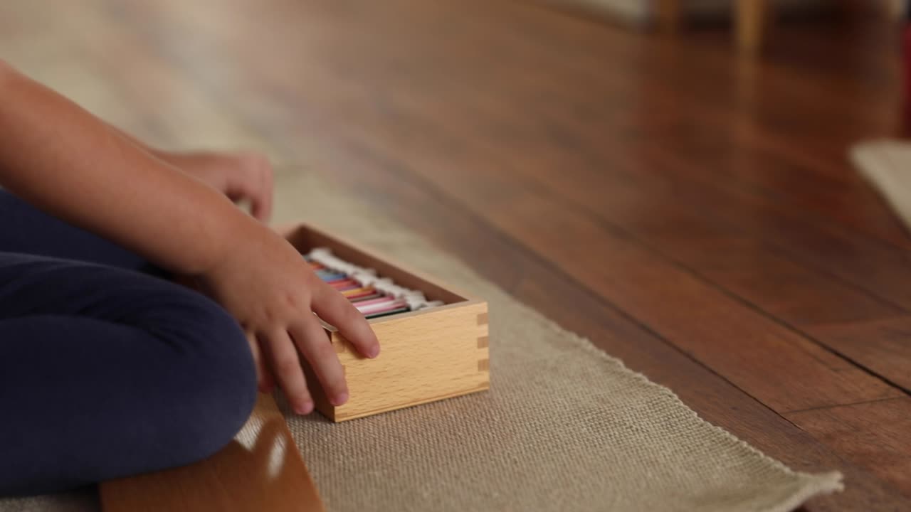 Child sitting on the floor organizing a stack of color cards in a classroom environment