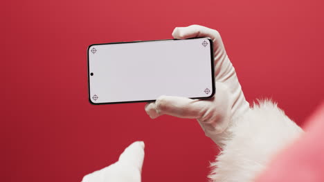 video de papá noel usando un teléfono inteligente con espacio de copia en fondo rojo