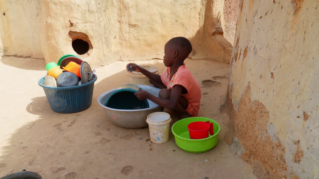 Black african young child children kid washing dishes in remote rural ...