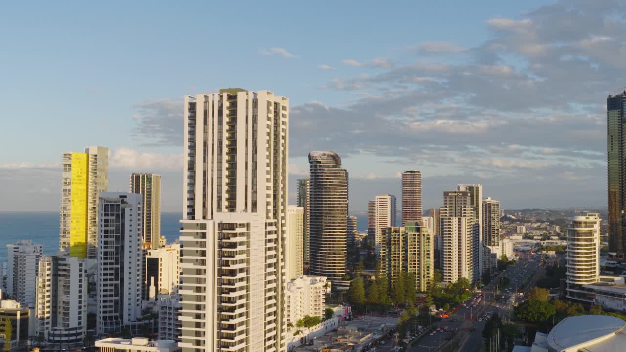 Drone captures Gold Coast's skyline with skyscrapers and ocean backdrop. Soft evening light enhances the vibrant cityscape