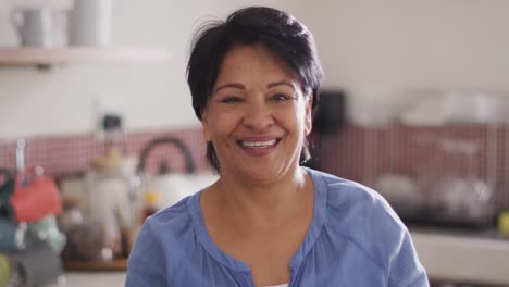 portrait of smiling senior biracial woman in kitchen alone