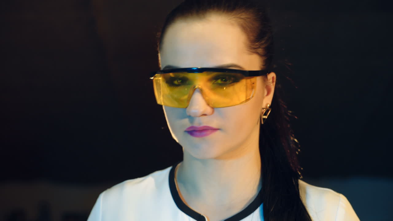 beautiful nurse with a hairdo is putting on eyeglasses with yellow glass and smiling in the laboratory