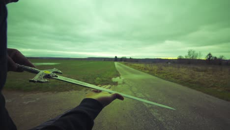 modern black swordsman warrior awaiting battle opponent in open field under green sky, europe, 4k | muscular, intimidating, shadow, figure, blurry, dark clothes, powerful, over the shoulder, examine