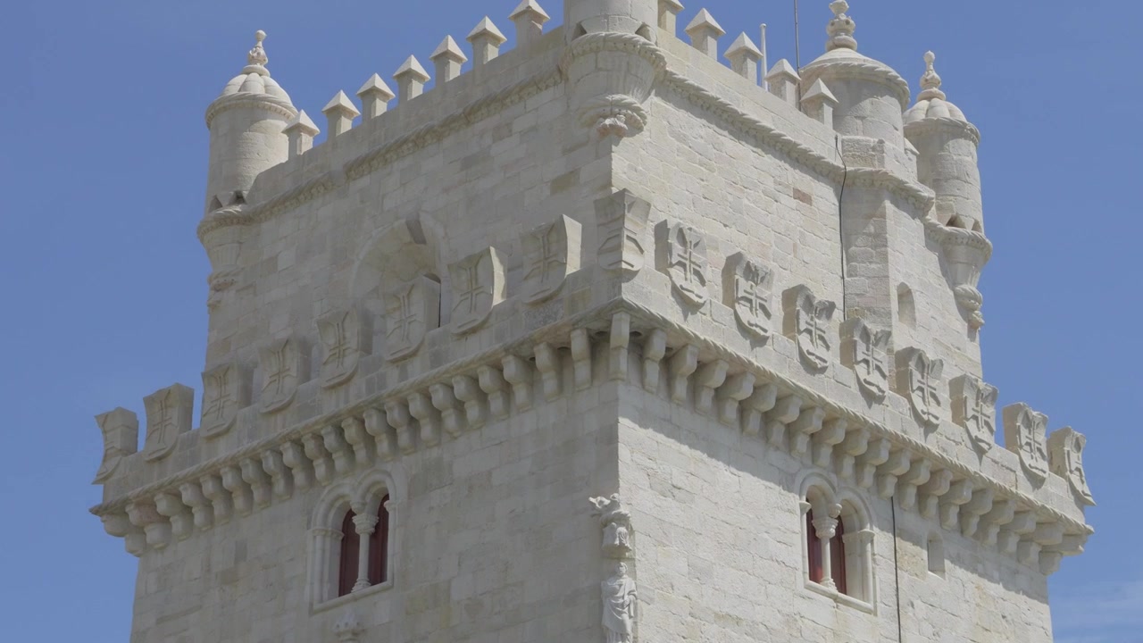 Merli in pietra calcarea, torrette e scudi con croci intagliate della Torre di Belém sotto un cielo blu, Lisbona