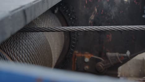 large rusty machine gear turns slowly letting go an iron cable