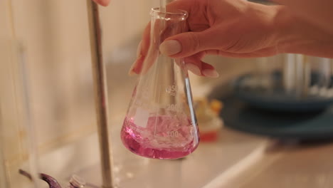 person pouring liquid into a flask in a lab setting