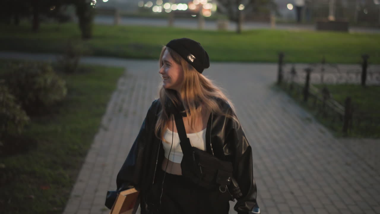 park path night woman walking away under lamplight, hands in leather jacket and beanie quiet atmosphere with distant city glow, contemplative pace, subtle silhouette and nostalgic mood as she departs