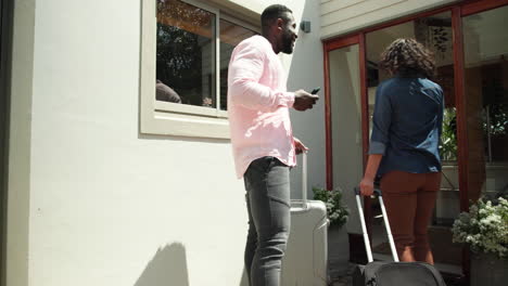 man and woman arriving home with luggage, entering house