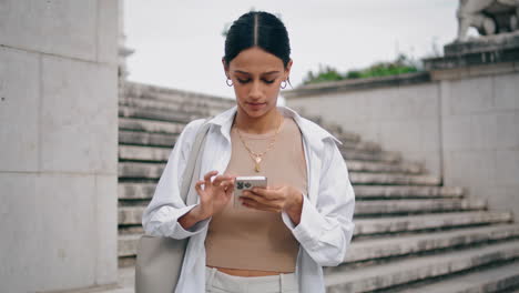 mujer molesta leyendo teléfono móvil ar escaleras verticalmente. mujer nerviosa escribiendo sms