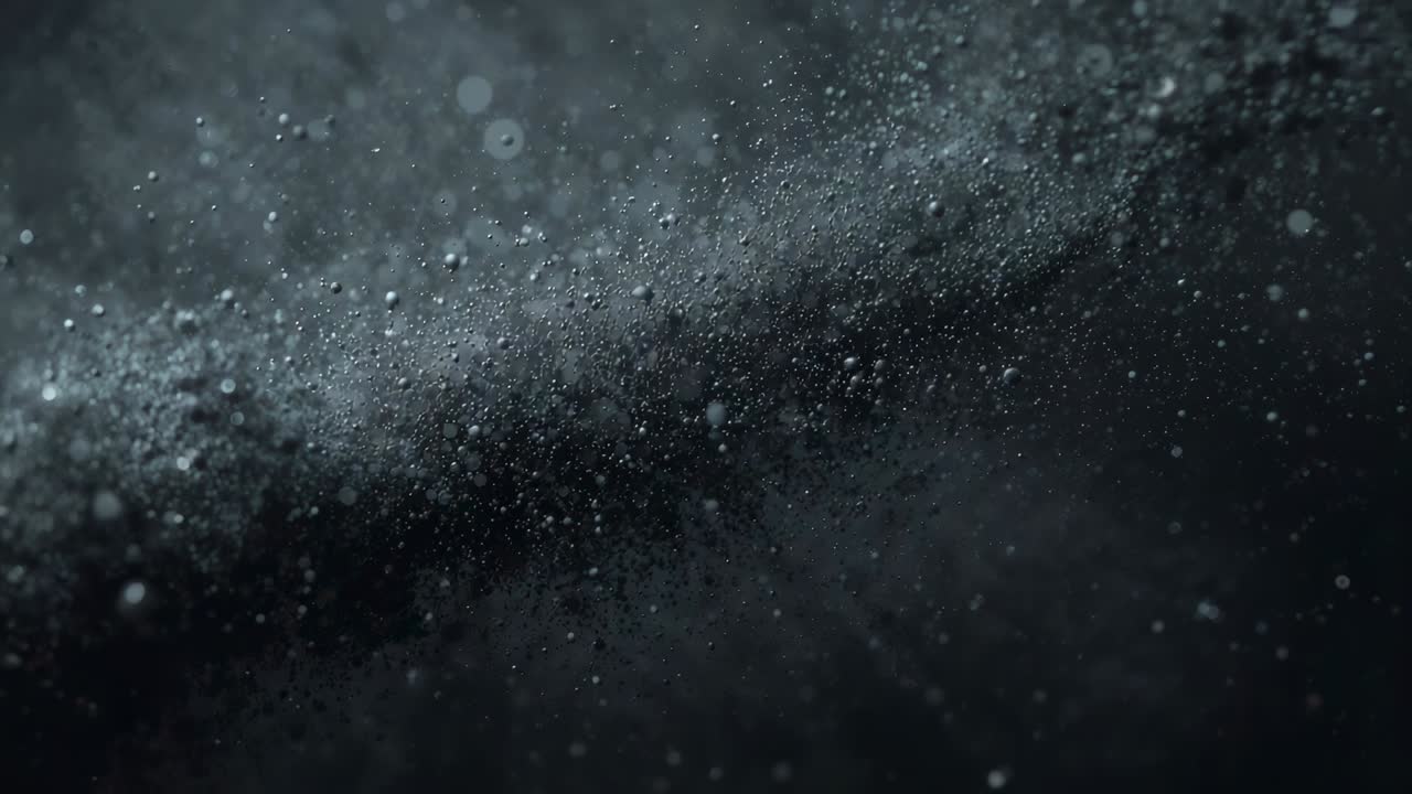 Drifting band of fine dust and spray across dark backdrop, lighting creating bokeh and showing flow