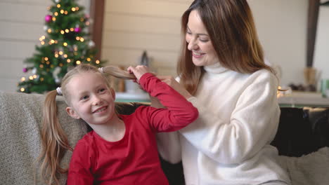 Mutter-Und-Tochter-Sitzen-Auf-Dem-Sofa,-Bedeckt-Von-Einer-Decke,-Während-Sie-Sich-Im-Wohnzimmer-Mit-Weihnachtsdekoration-Unterhalten-4