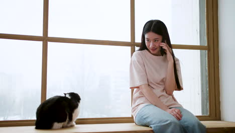 mujer con gato junto a la ventana