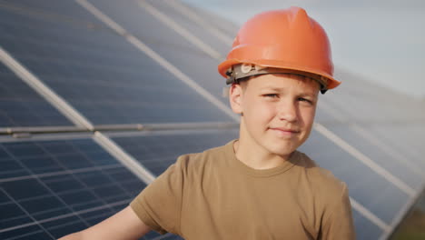 young boy wearing a safety helmet inspecting solar panels