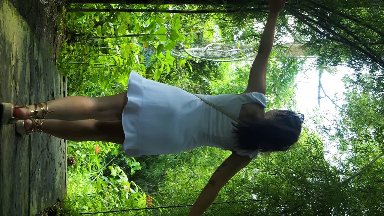 Slow motion dolly shot of a young woman in white dress with outstretched arms walking through an avenue of plums on her adventurous journey on bali in indonesia