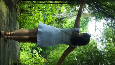 foto en cámara lenta de una mujer joven con vestido blanco con los brazos extendidos caminando por una avenida de ciruelas en su aventurero viaje a bali en indonesia