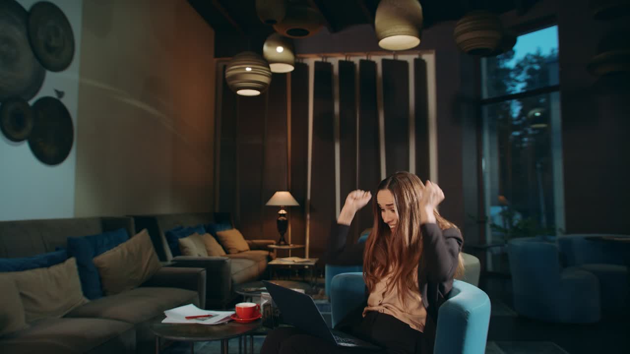 Begejstret forretningskvinde nyder gode nyheder på bærbar computer i kontorlounge.