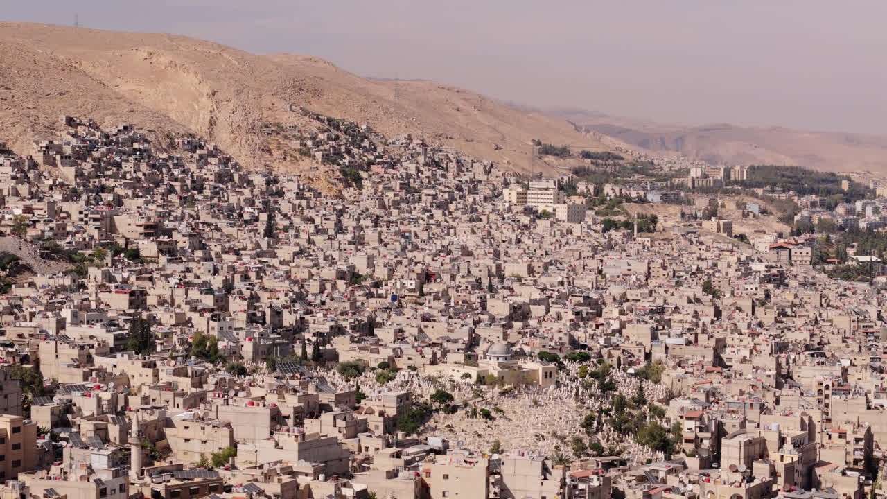 Drone slides sideways over Damascus, Syria during daytime, revealing the city’s architecture, streets, and urban layout from above
