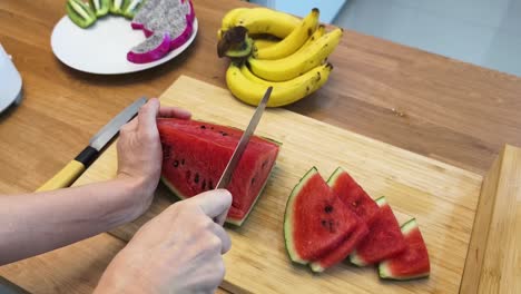 cutting watermelon on a wooden board in a kitchen