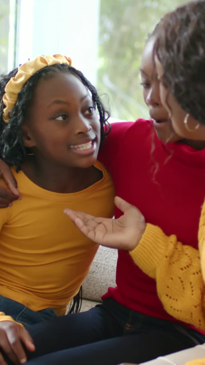 Vertical video: Hearing mother's words girl in mustard top lifting chin, speaking on couch