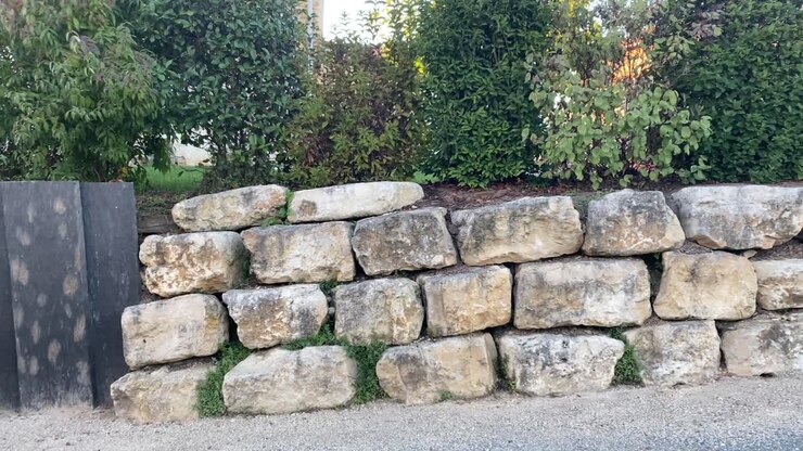 Stone wall made with large blocks with greenery behind