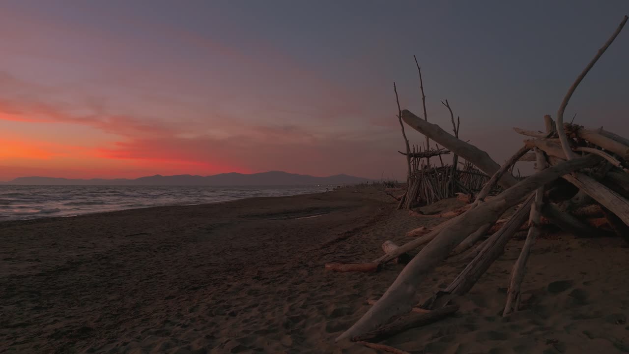Tipi in legno su una spiaggia sabbiosa al tramonto.