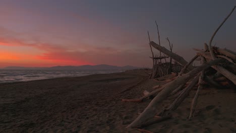 wooden tipis on a sandy beach at sunset