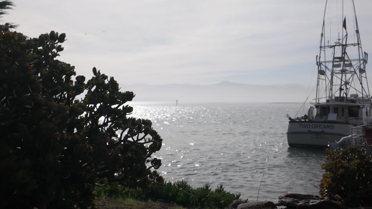 Gimbal close-up panning shot of docked fishing vessels in serene Morro Bay, California. 4K at 60 FPS Slow Motion
