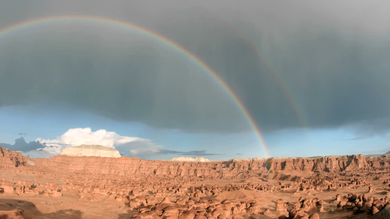 un arco iris se arquea sobre el parque estatal goblin valley