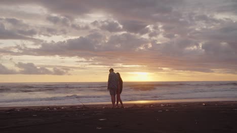 pareja joven caminando en la playa en la costa de bali al atardecer