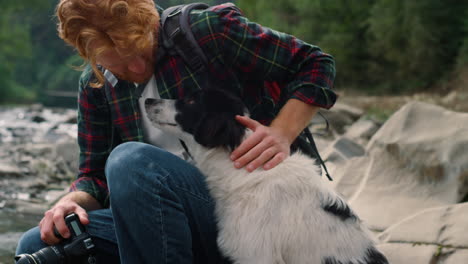 Male-hiker-sitting-at-river-with-dog