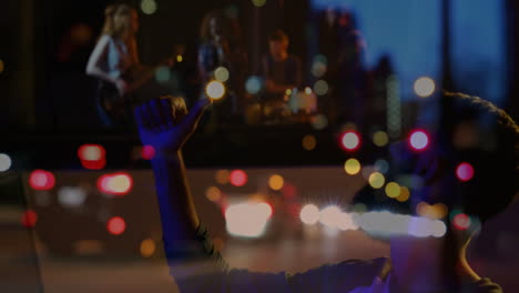 man silhouette giving thumbs-up toward window pane, band playing music in spotlight with car lights