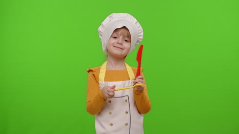niña vestida de chef cocinero con tenedor y cuchillo, agitando la cabeza de aprobación en el fondo de la llave cromada