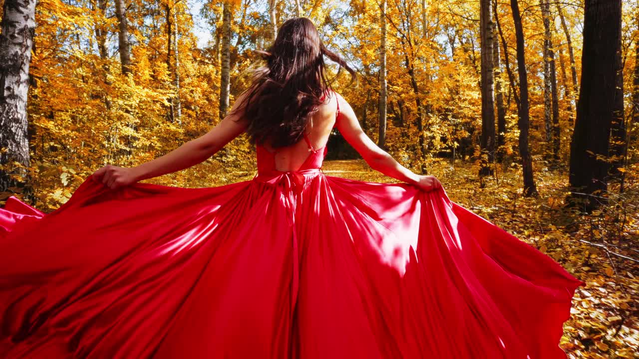 A Captivating Journey Through Autumn's Embrace: Woman in Flowing Red Dress Amidst Golden Leaves and Majestic Trees