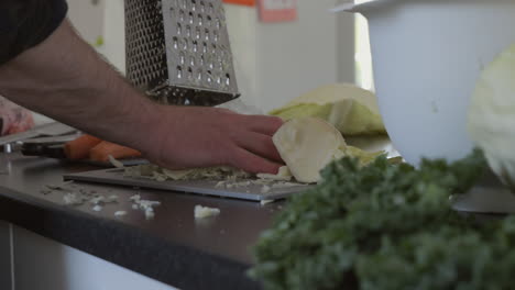 Slow-motion-shot-of-male-hand-grab-fresh-sliced-cabbage-after-using-inox-grater,-dolly-motion