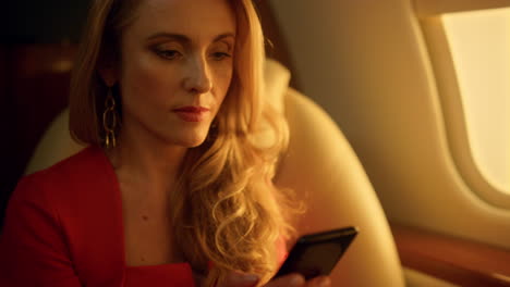 Smiling-woman-flying-jet-closeup.-Happy-passenger-using-smartphone-on-plane.