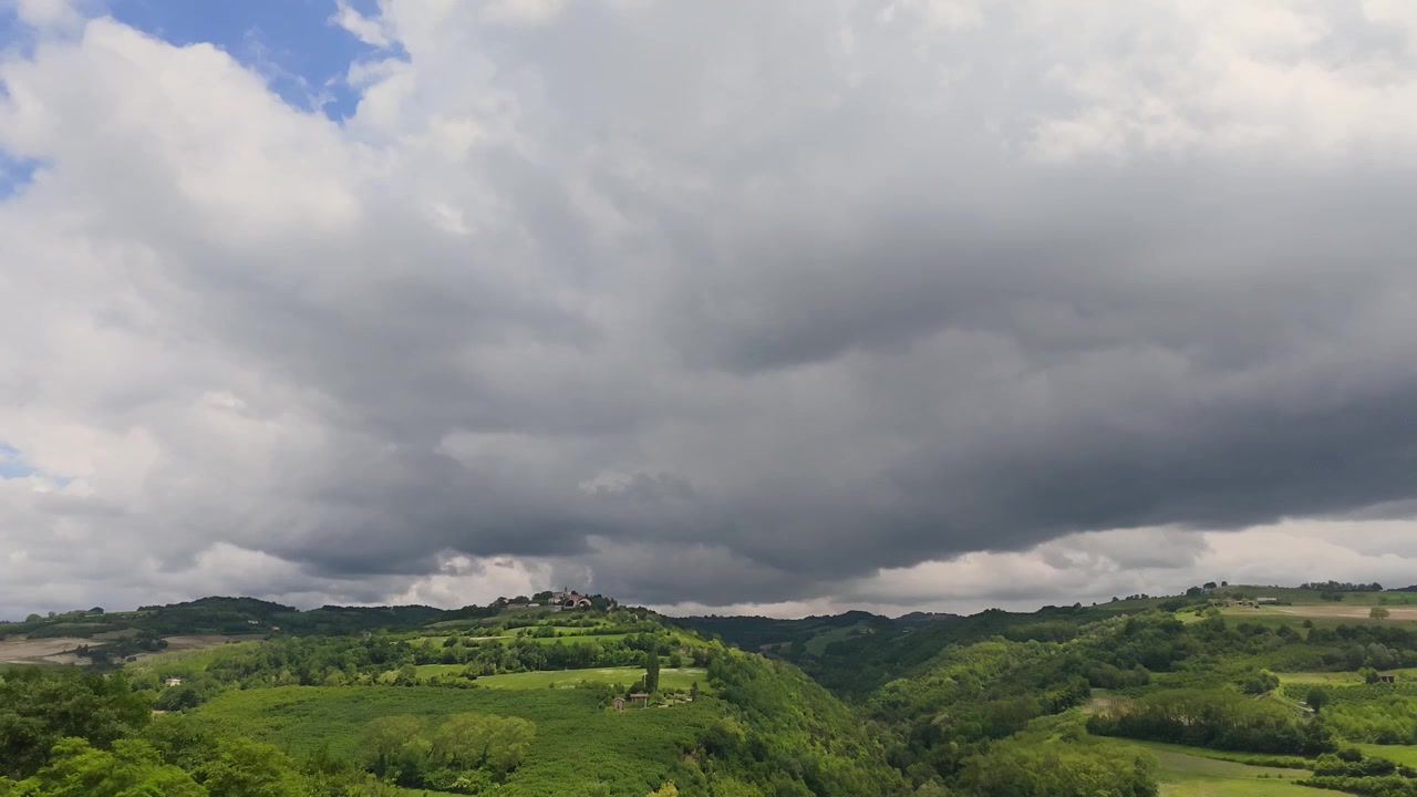 Un timelapse grandangolare cattura nuvole temporalesche scure che passano sopra dolci colline verdi e vigneti.