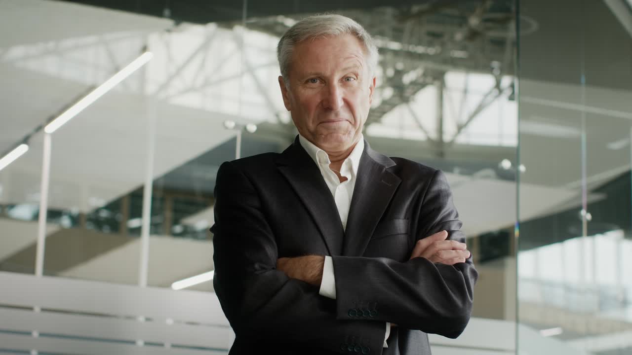 empresario maduro exitoso cruzando las manos de pie en el centro de negocios moderno