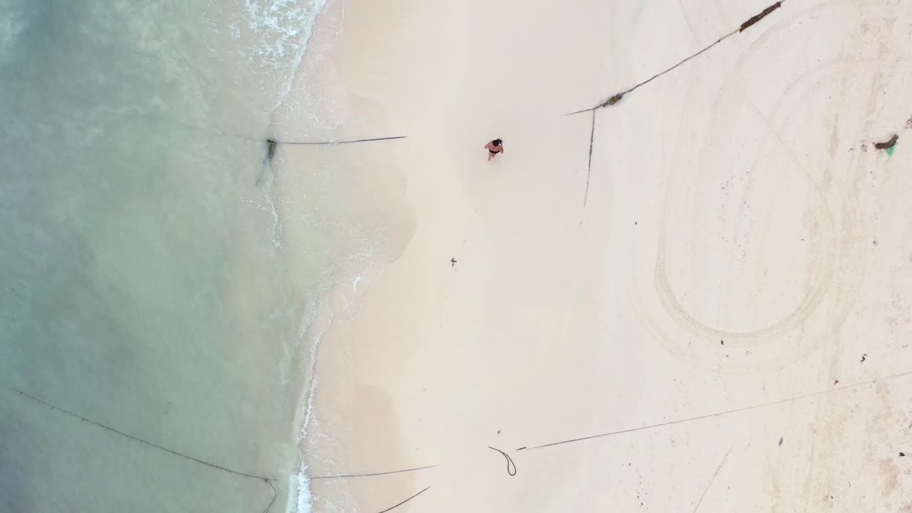 플라야 델 카르멘 멕시코의 빈 백사장에서 달리는 청년의 공중 탑다운