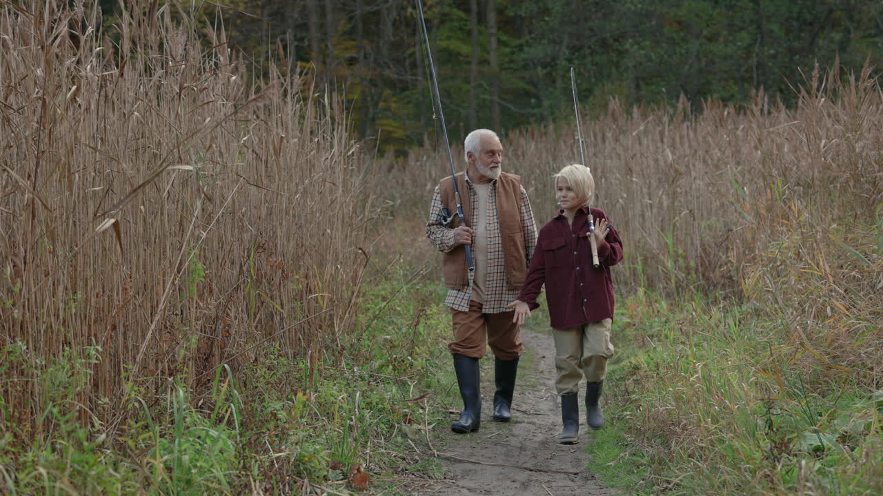 Grandfather and Grandson Walking with Fishing Rods on a Nature Path