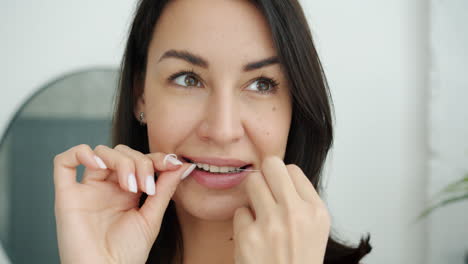 mujer lavándose los dientes con hilo dental