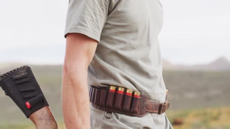 Caucasian-male-survivalist-holding-hunting-rifle,-looking-to-distance-in-wilderness,-smiling