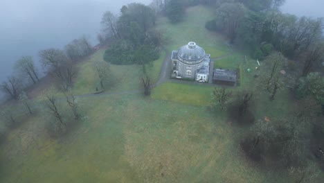 Drone-partially-orbiting-over-a-private-estate,-located-in-the-middle-of-the-Windermere-Lake,-in-t-he-town-of-Bowness-on-Windermere-in-Westmorland,-England