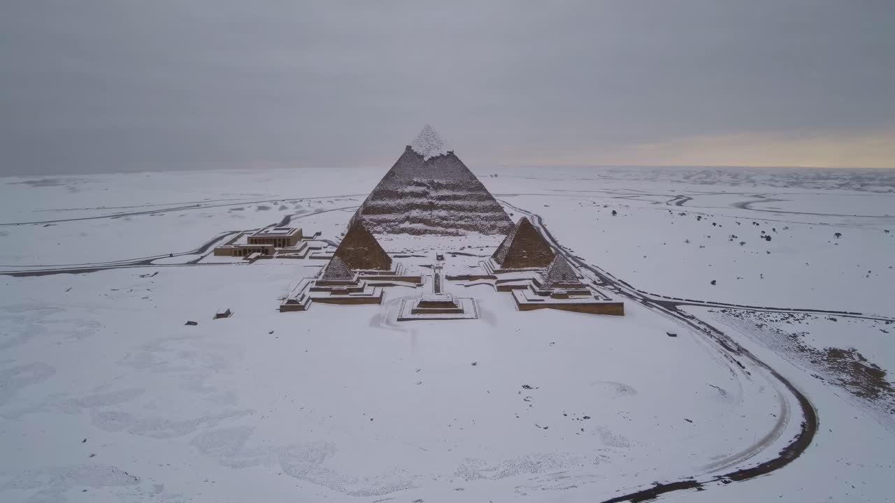 Aerial video captures snow-covered pyramids, showcasing a surreal blend of ancient architecture