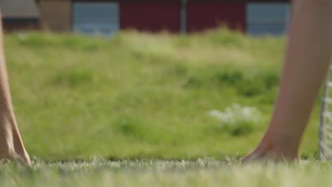 nahaufnahme einer gruppe junger leute, die barfuß durch das grüne gras laufen, auf dem weg zum beachvolleyball