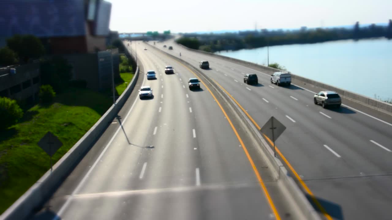 Tilt Shift footage of traffic on Interstate 64 in Louisville, KY, River on right side of road, shot from overpass