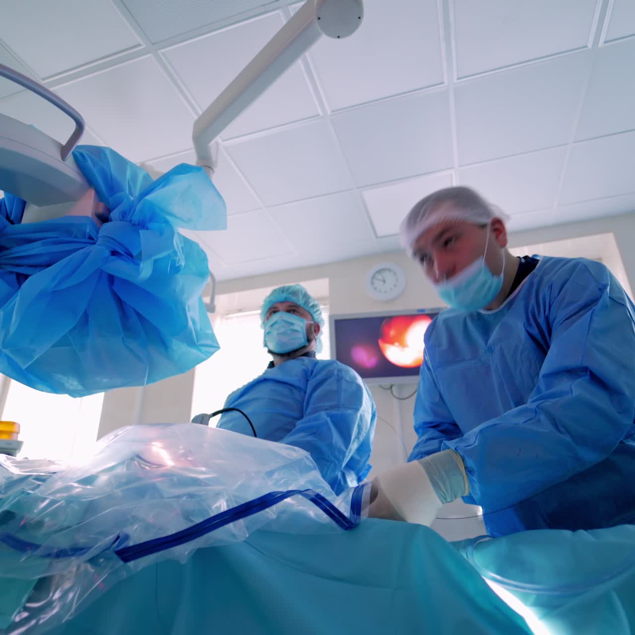 Group of doctors in the operating room. Medical specialists in blue masks and uniform are performing an operation in clinic. Medical surgery. Video