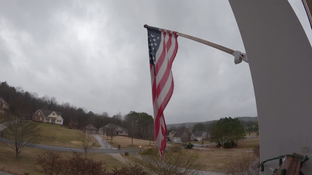suburbios americanos sombríos nublados bandera de estados unidos que sopla en el viento timelapse