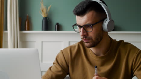 vista de cerca de un estudiante con auriculares y usando una computadora portátil sentado en la mesa 1